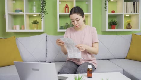 Asian-young-woman-reading-medicine-leaflet-at-home.